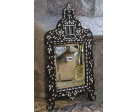 A small eastern hardwood wall mirror with shaped outline and inset mother of pearl detail, surrounding a rectangular bevelled