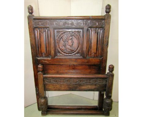 A pair of antique style oak bedsteads, the panelled headboards with linen fold and portrait detail, beneath turned baluster f