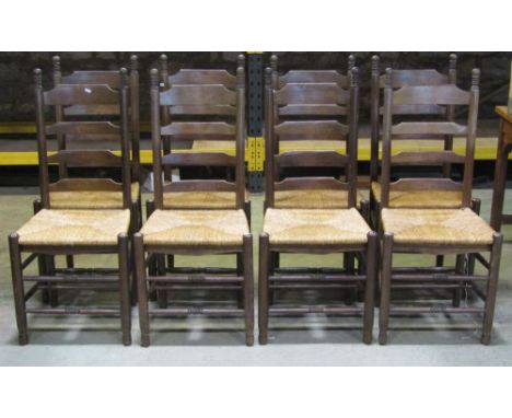 A set of eight oak graduated ladder back dining chairs with rush seats, turned supports and stretchers 