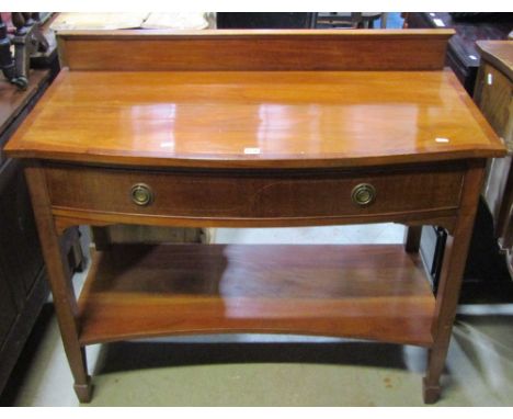 An inlaid Edwardian mahogany bow fronted two tier side table, with crossbanded and string inlaid detail, fitted with a frieze