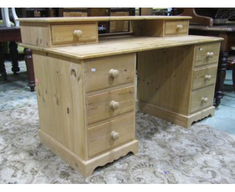 A contemporary stripped pine kneehole twin pedestal desk, each pedestal fitted with three drawers, beneath a removable raised