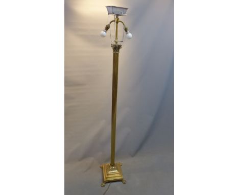 A 20th Century brass corinthium column standard lamp raised on paw feet