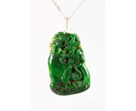 A CARVED JADE PENDANT, carved with a stork and almond blossom, 5cms long on a silver chain.