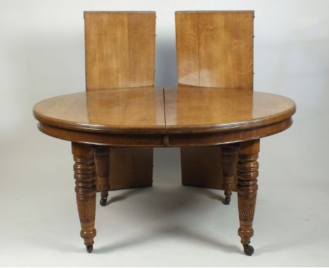 A Victorian oak D-end extending dining table, the bevelled top with two extra leaves and raised on ring turned and wrythen re