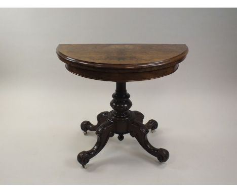 A Victorian figured walnut fold-over top card table of half round form enclosing a claret baize lined playing surface on a tu