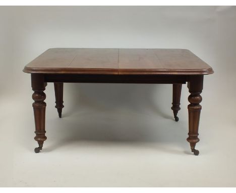 A Victorian mahogany wind-out extending dining table, the bevelled rectangular top with rounded corners and raised on fluted 