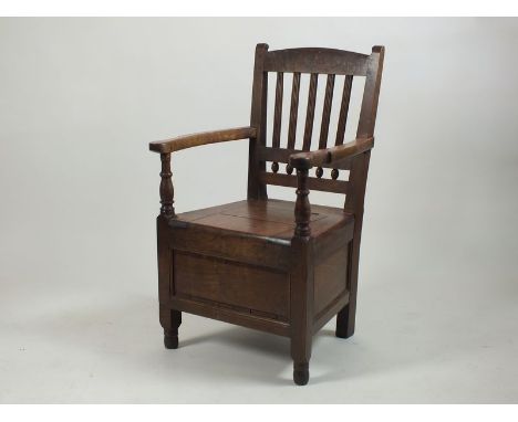 Early 19th century oak commode arm chair with railed back and lift top seat raised on squat ring turned feet, lacking ceramic