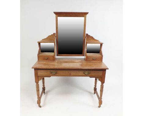 An Edwardian walnut dressing table with bevelled rectangular mirror plate between two gallery drawers below mirror backs, the