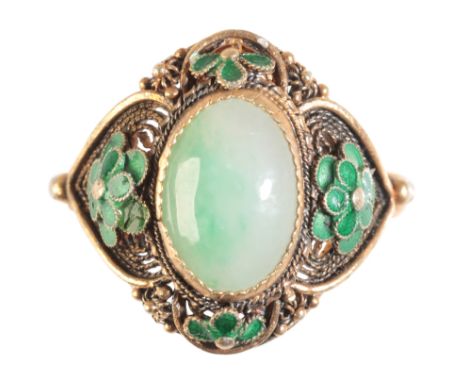 A GOLD COLOURED METAL, JADE AND GREEN ENAMEL RING the oval cabochon jade approx 2ct, surrounded by four leaf clusters and fil