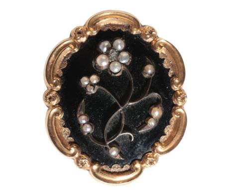 A VICTORIAN GOLD COLOURED METAL, SEED PEARL AND DIAMOND MOURNING BROOCH worked in relief with a scrolled flower on a black en