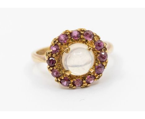 A ruby and moonstone set 9ct gold cluster ring, comprising a claw set round cabochon moonstone, approx 6mm, within a border o