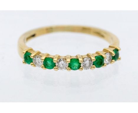 A nine stone diamond and emerald 18ct gold half eternity ring, comprising claw set round brilliant cut diamonds and round mix