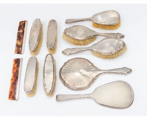 A collection of early 20th Century engine turned silver mounted dressing table sets to include eight various brushes, two mir