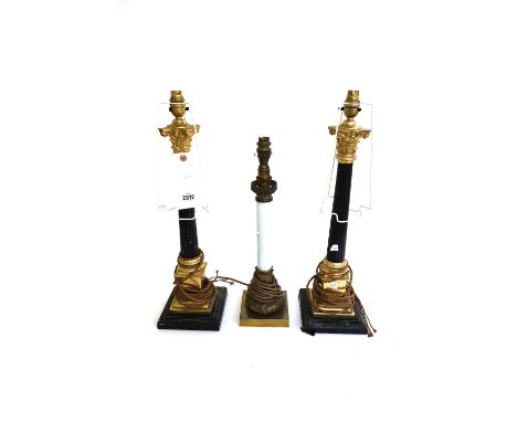 A pair of gilt and ebonised table lamps of Corinthian column form (48.5cm high) and a smaller similar table lamp. (3)