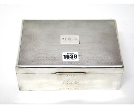 A silver rectangular table cigar box, wooden lined within, the hinged lid engine turned, presentation inscribed, London 1939.