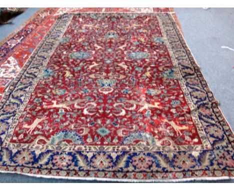 A Tabriz carpet, Persian, the burgundy field with palmettes, cartouches, hunting animals, an indigo palmette and leaf border,