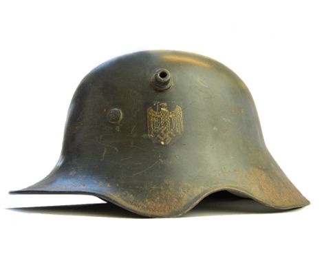 A World War Two German army helmet, green painted with applied Waffen mark, shaped rim and original leather lining.  Illustra