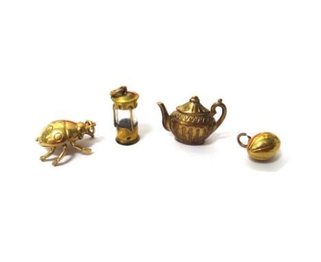 Four 9ct gold charms, comprising;  a teapot, a ladybird, a rugby ball and a miner's lamp, combined gross weight 9.6 gms.