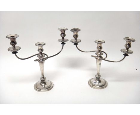 A pair of plated three light table candelabra, each having fluted scrolling arms, gadrooned rims and raised on a circular bas