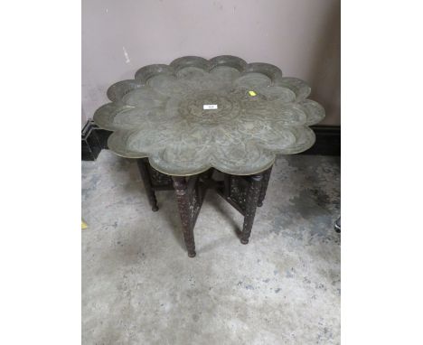 A VINTAGE EASTERN BRASS TOPPED TABLE ON CARVED FOLDING STAND