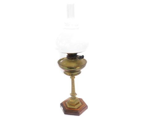 An early 20thC Williams and Bach brass oil lamp, raised on a hexagonal mahogany and satinwood banded base, with glass chimney