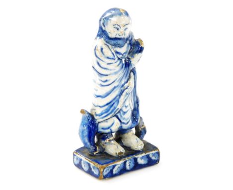 An 18thC tin glazed earthenware figure modelled as an Oriental gentleman in cloak, on a square leaf decorated base, 15cm high