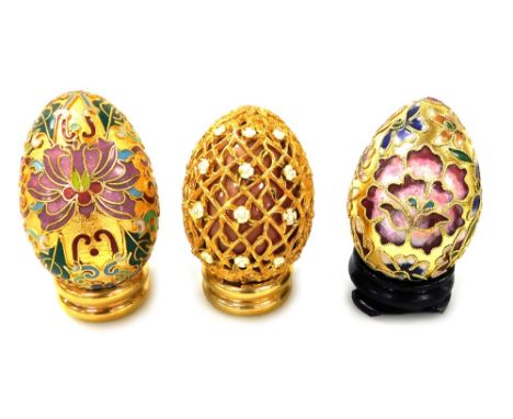 Two Chinese cloisonne enamel eggs on stands, and an egg with gilt metal and floral enamelled overlay. (3) 