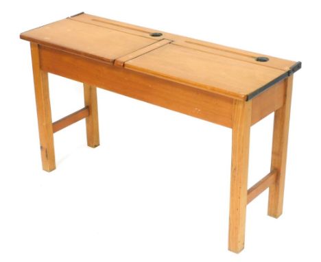 An early 20thC oak and beech twin school desk, with two hinge lids, with pen recesses and inkwell recesses behind, raised on 