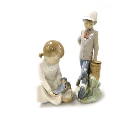 A Nao porcelain figure of a boy, modelled standing with a puppy looking up at him, and a further Nao figure of a girl placing