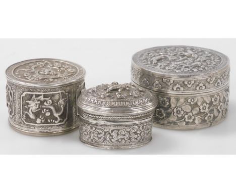 Two Indian white metal trinket boxes, each with embossed decoration, one of cylindrical form, decorated with birds and flower