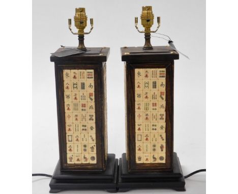 A pair of Chinese hardwood table lamps, of rectangular section, inlaid with panels of mahjong counters, raised on a stepped b