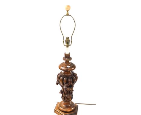 A Spanish carved wooden table lamp, with foliate scroll body, raised on a hexagonal base, 79cm high.