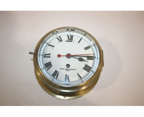 BRASS SHIPS CLOCK by Smiths English Clocks Ltd, London, with a white enamel dial and brass case. With it's key, dial 17cms di