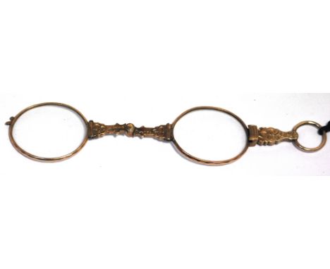 A yellow metal lorgnette on a cord, oval lenses in faceted rim.