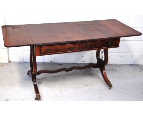 A reproduction mahogany sofa table with two central drawers on lyre supports and brass feet, extended length 154cm.