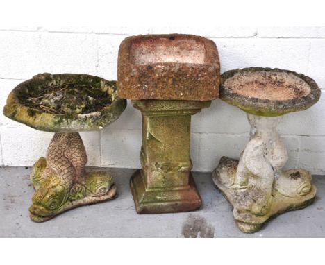 Three composite stone birdbaths, two with serpentine supports and a further example of column form with a square section base