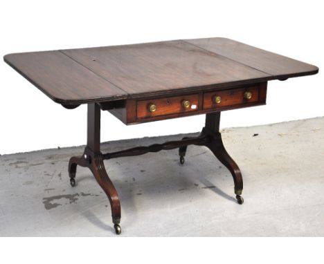 A late George III mahogany sofa table, the rectangular top with twin rounded flaps above four frieze drawers raised on fluted