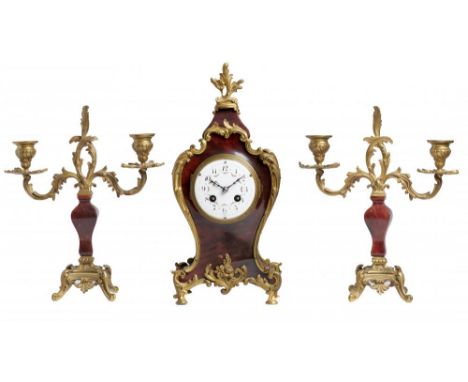 A FRENCH GILT BRASS MOUNTED RED STAINED HORN AND EBONISED MANTEL CLOCK AND PAIR OF SIMILAR CONTEMPORARY CANDELABRA, C1900 the