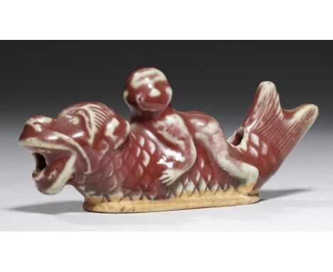 A CHINESE PORCELAIN WATER DROPPER MODELLED AS A BOY ON THE BACK OF A FISH TAILED CREATURE, QING DYNASTY  the flambé glaze rev