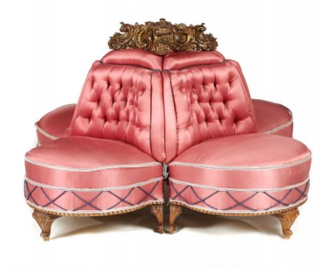 A WALNUT 'SOCIABLE'  SOFA, LATE 19TH C  of four rounded seats, covered in buttoned pink satin and surmounted by a carved and 