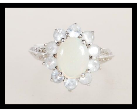 A hallmarked 9ct white gold opal and white stone cluster ring having a central opal panel with a halo of white stones. Weighs