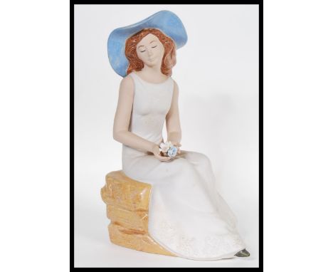 A 20th Ceramic figurine in the manner of Lladro by Nadal, the figurine modelled as a seated young female, stamped to base. Me