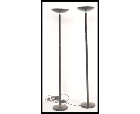 A pair of 20th Century ebonised tubular up-lighter standard floor lights / lamps being raised on circular bases with concave 