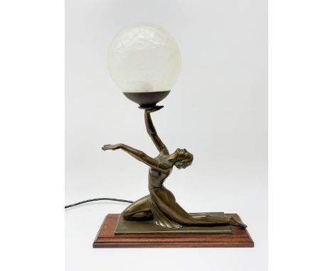 A bronzed Art Deco style table lamp in the form of a dancer, supporting a globular glass shade, overall H45.5cm.Click here to