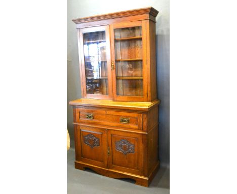 An Arts and Crafts Oak Secretaire Bookcase, the moulded cornice above two glazed doors enclosing shelves, the lower section w