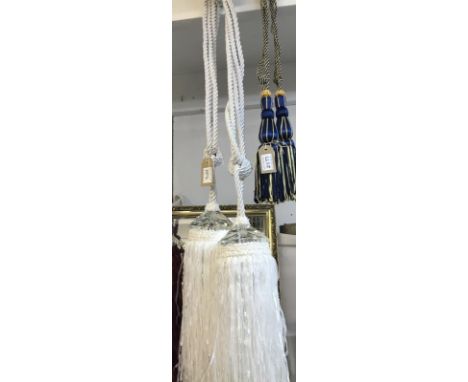 A pair of white curtain tie backs with gem style embellishment and tassels