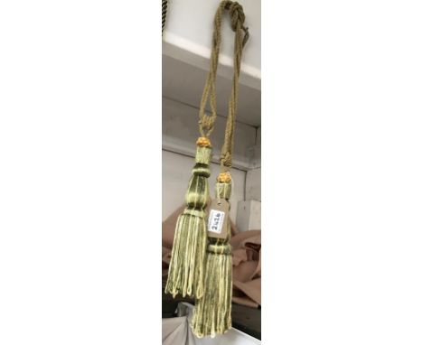 A pair of green and gold curtain tie backs with tassels