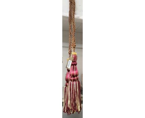 A pair of red and gold curtain tie backs with tassels