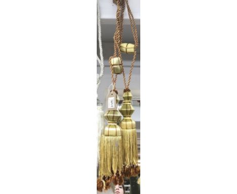 A pair of gold and burnt orange curtain tie backs with tassel