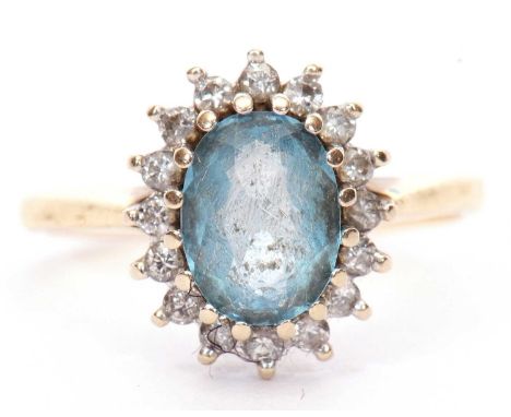 Light blue stone and diamond cluster ring, the oval shaped stone multiclaw set and raised above a small diamond surround, sta